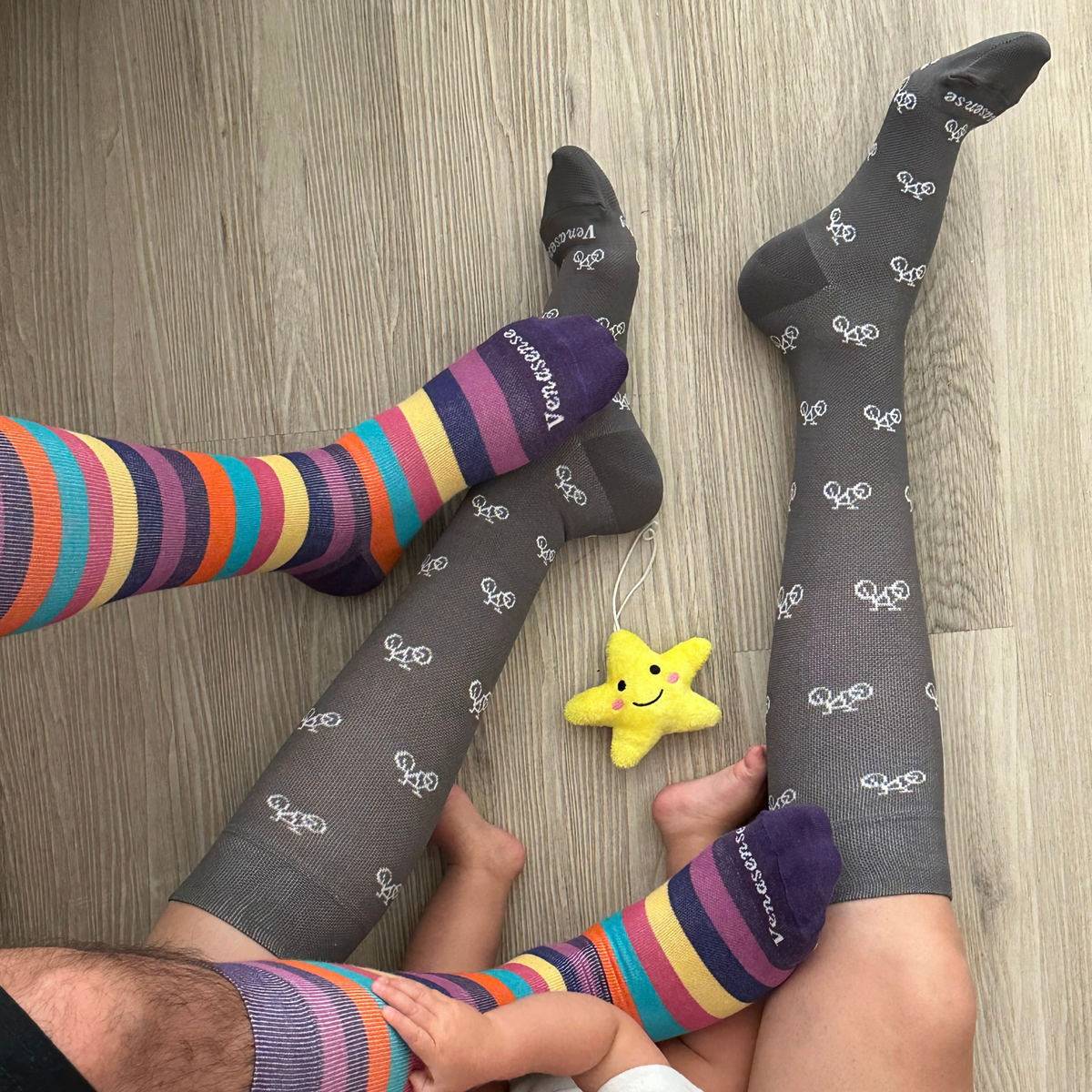 Knee-High Compression Socks in Gray Bicycles and Rainbow Pink – worn by family members at home on a wood floor, lifestyle photo
