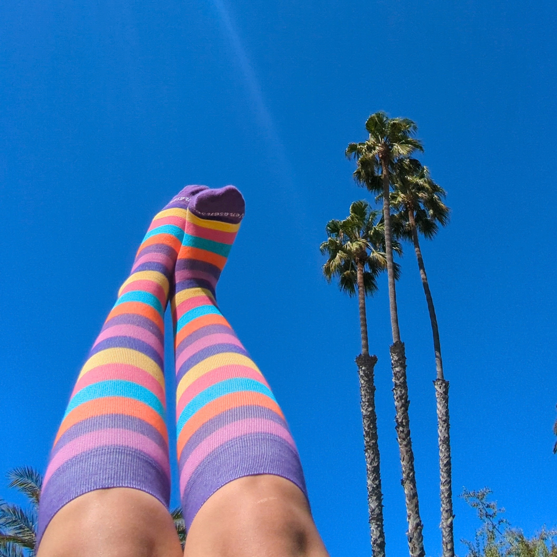 Woman wearing colorful rainbow knee-high compression socks outdoors