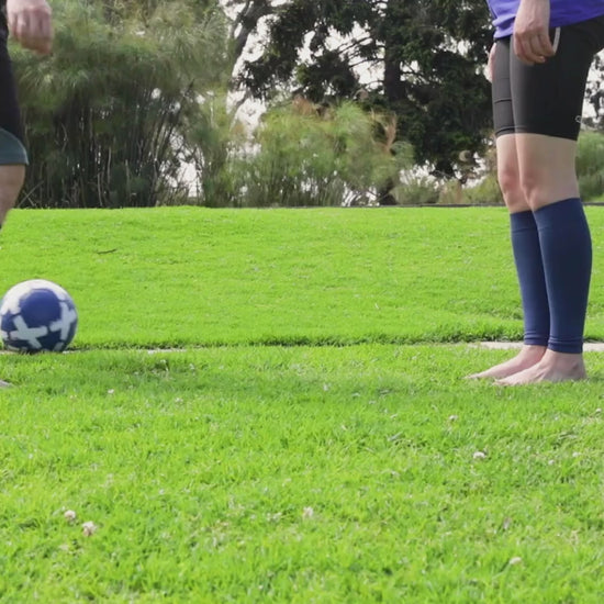 Two people playing soccer while using Venasense compression calf sleeves