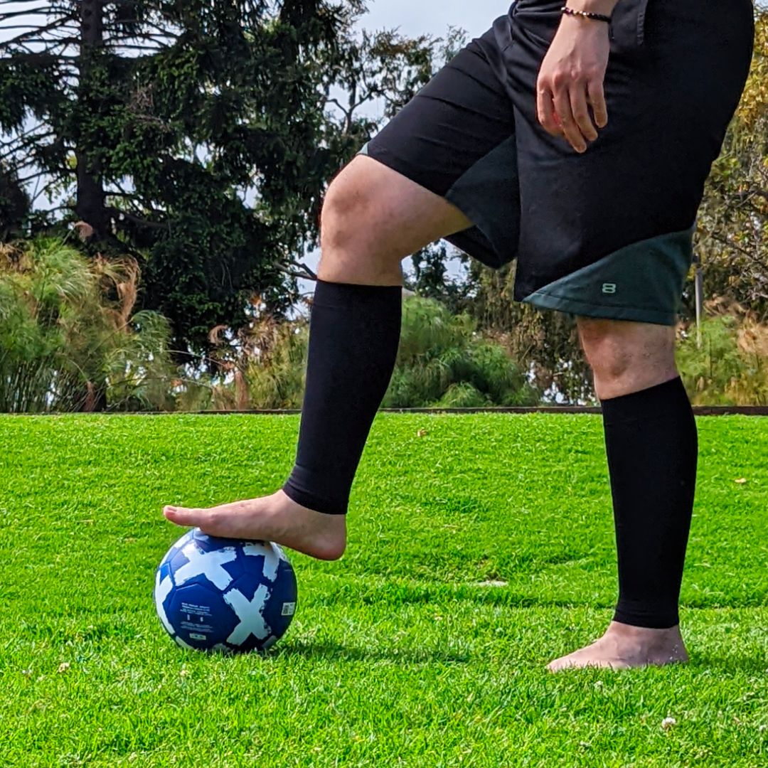 Men legs wearing Venasense Black Compression Calf Sleeves while playing soccer